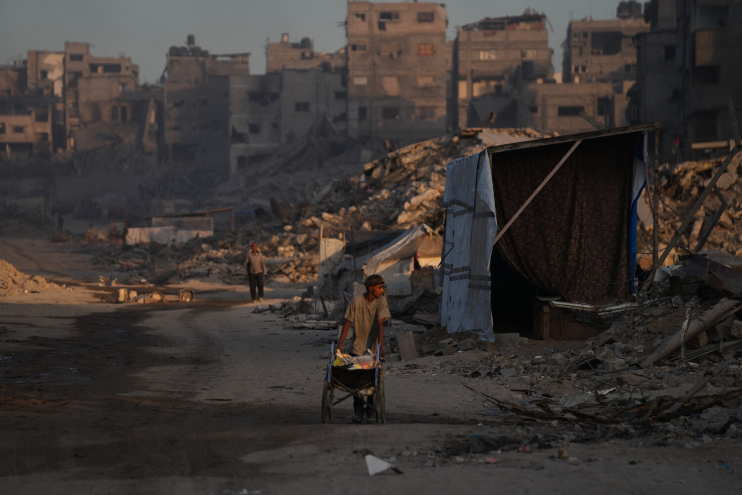 Palestinians walk trough the destruction caused by the Israeli air and ground offensive in Sheikh R...