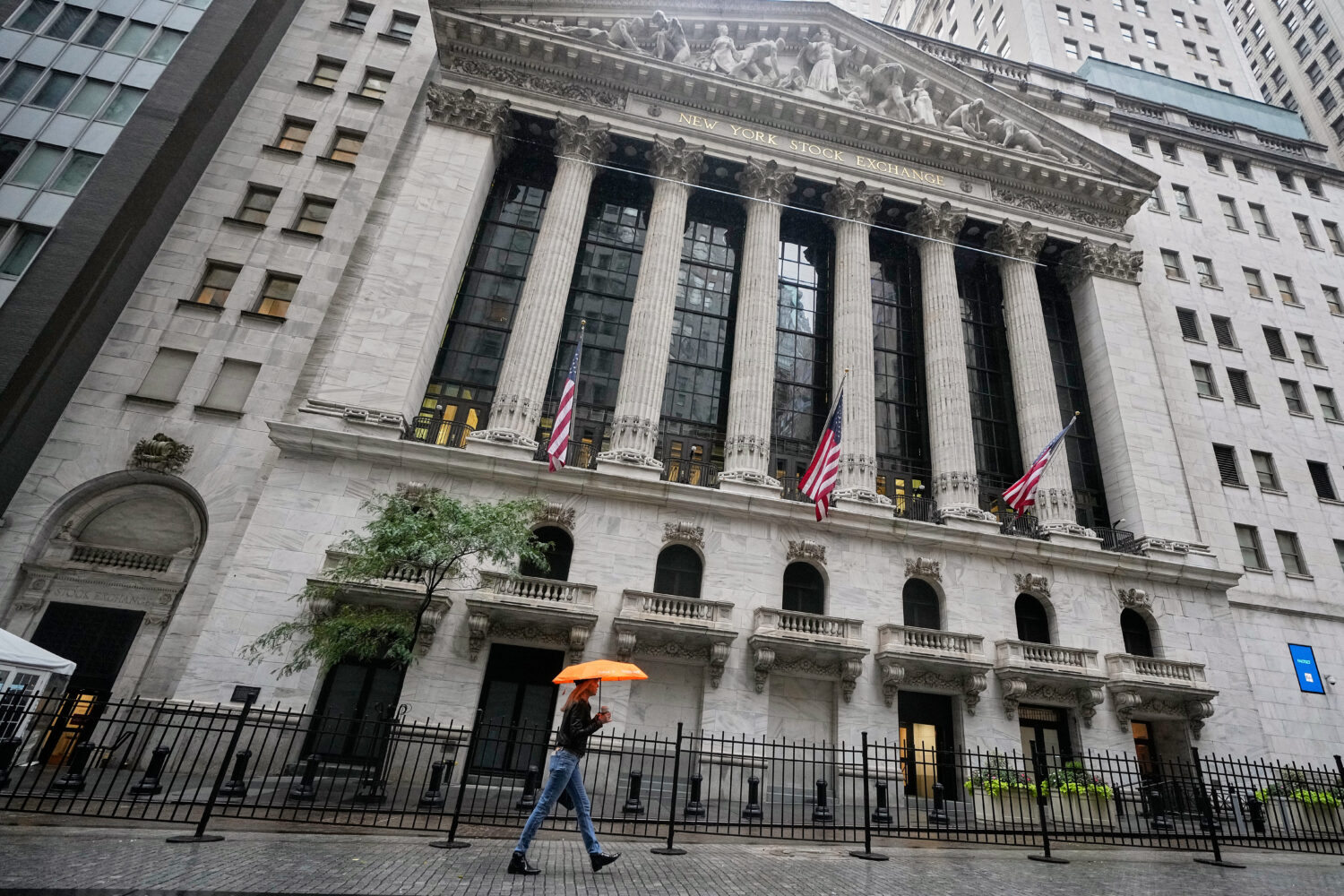 A woman with an umbrella passes the New York Stock Exchange, Monday, Oct. 13, 2025. (AP Photo/Richa...