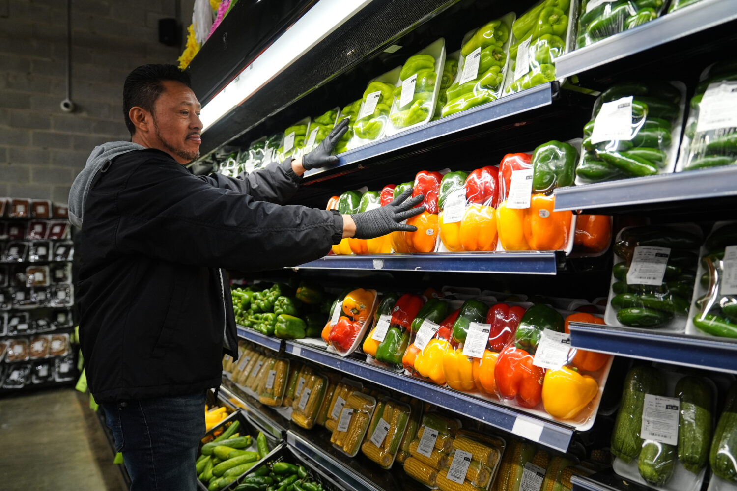 A grocery store employee stocks produce, which is covered by the USDA Supplemental Nutrition Assist...