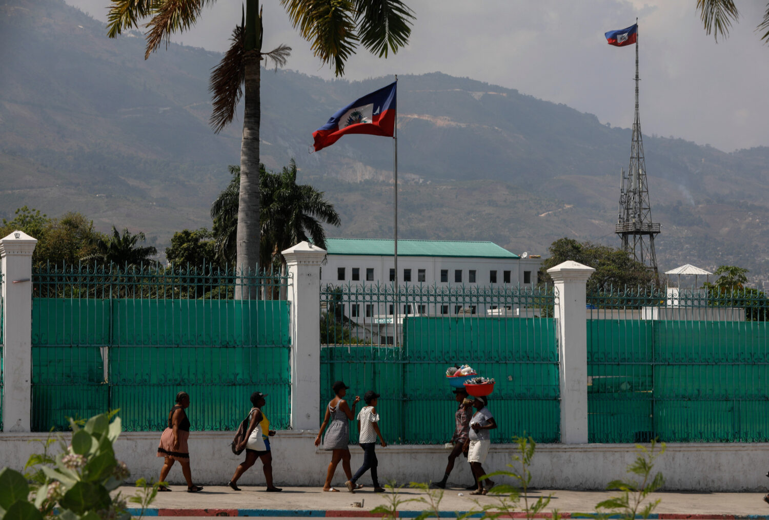 FILE - People walk past the National Palace in Port-au-Prince, Haiti, March 25, 2024. (AP Photo/Ode...