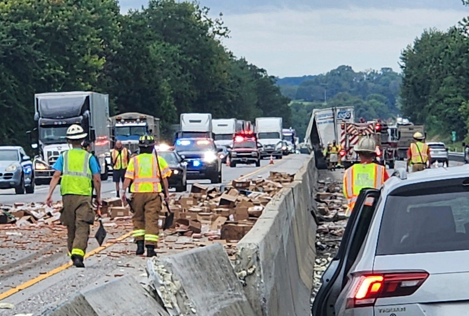Rescue crews clean up a truckload of hot dogs that spilled out of a tractor-trailer on Friday, Augu...