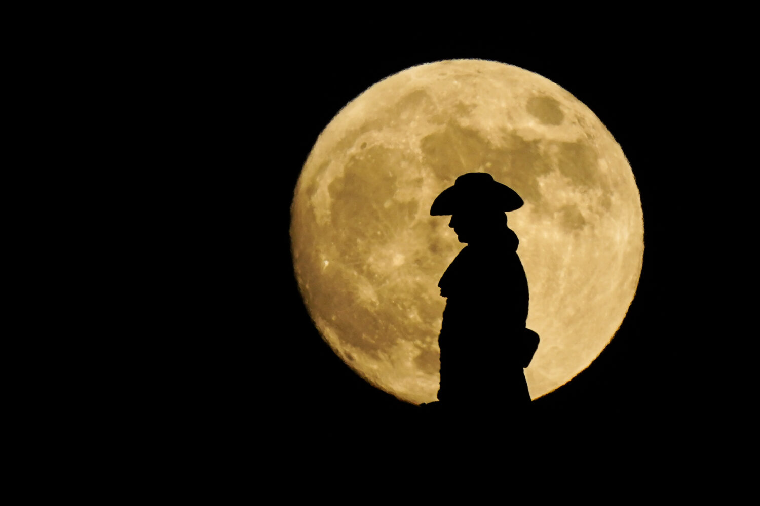 FILE - A strawberry full moon rises behind a statue of William Penn atop City Hall in Philadelphia,...